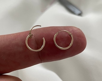 以下が含まれることがあります： 金色のフープイヤリングのペア。イヤリングは小さく繊細で、毎日の着用に最適です。