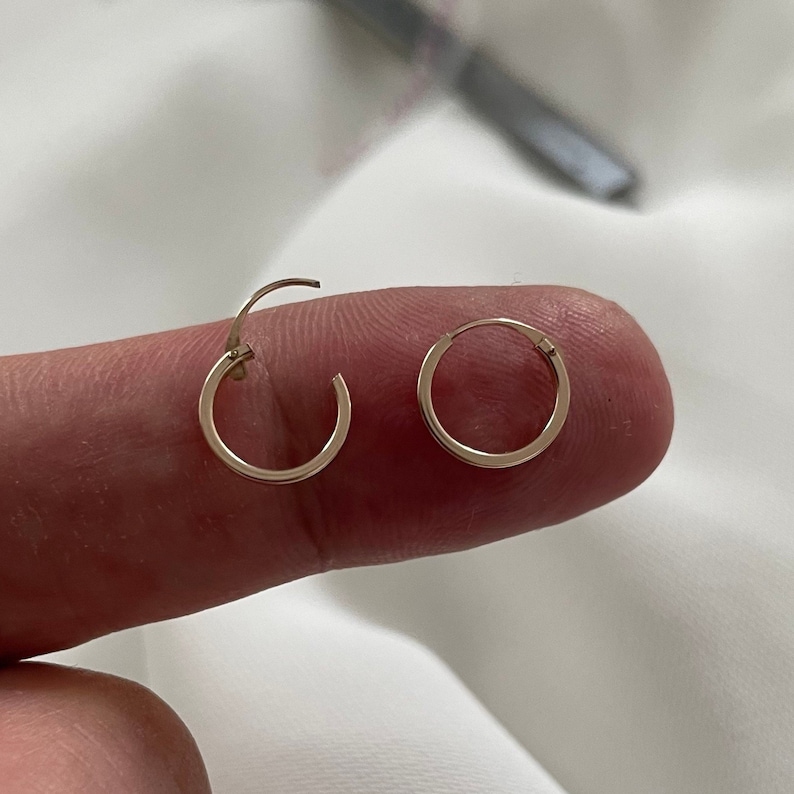 May include: A pair of gold hoop earrings. The earrings are small and delicate, and they are perfect for everyday wear.