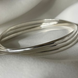 May include: A silver bangle bracelet with three bands.