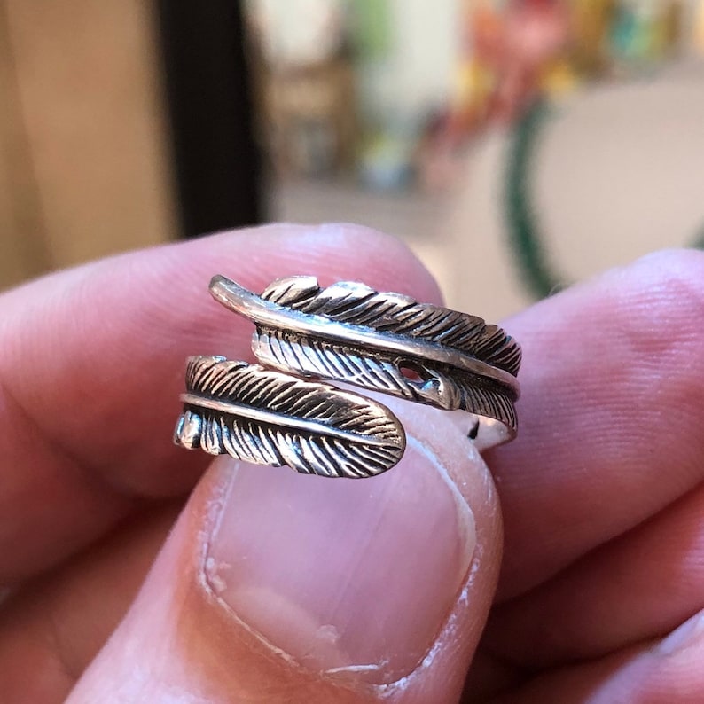 Puede incluir: Un anillo de plata con un dise&ntilde;o de pluma. El anillo es ajustable y se puede usar en cualquier dedo.