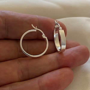 May include: A pair of silver hoop earrings. The earrings are simple and elegant, with a smooth, polished finish.