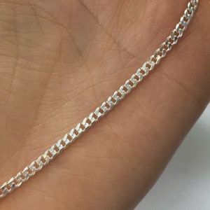 以下が含まれることがあります： 光沢のある仕上げのシルバー製のカーブチェーンネックレス。チェーンは、小さな相互に連結されたリンクでできています。