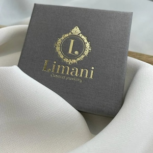 Op de afbeelding: Een grijze doos met een gouden logo met de tekst "L. Limani Klassieke Sieraden".