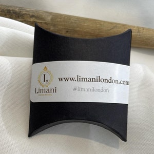 May include: A black pillow box with a white label that says "www.limanilondon.com" and "#limanilondon". The label also has a logo with the letter "L" and the word "Limani".