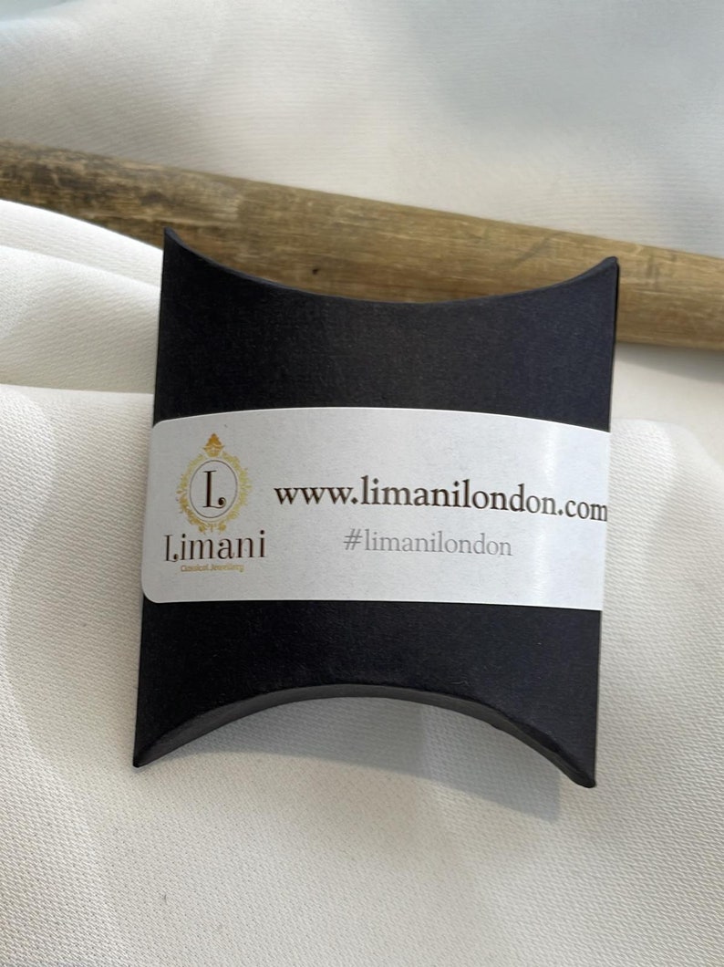 May include: A black pillow box with a white label that says "www.limanilondon.com" and "#limanilondon". The label also has a logo with the letter "L" and the word "Limani".