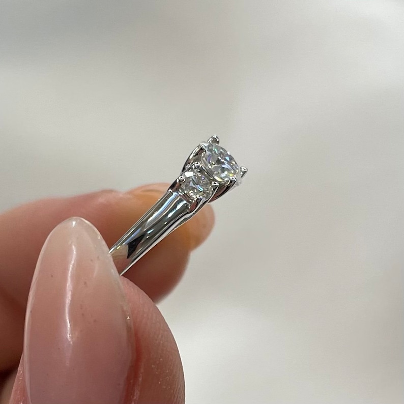 Puede incluir: Un anillo de plata con tres diamantes redondos. El diamante central es m&aacute;s grande que los dos diamantes laterales.