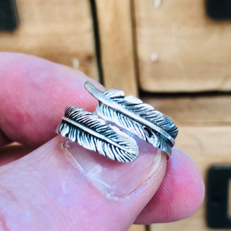 Puede incluir: Un anillo de plata con un dise&ntilde;o de doble pluma. El anillo es ajustable y se puede llevar en cualquier dedo.