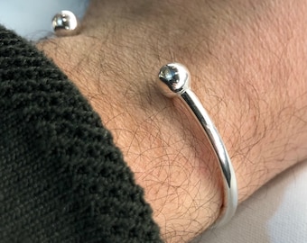 Op de afbeelding: Een zilveren armband met twee ronde bolletjes aan de uiteinden.