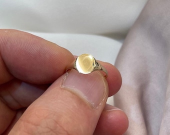 May include: A gold signet ring with a smooth, oval-shaped top.