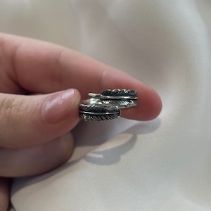 May include: A silver ring with a feather design. The ring is adjustable and can be worn on any finger.