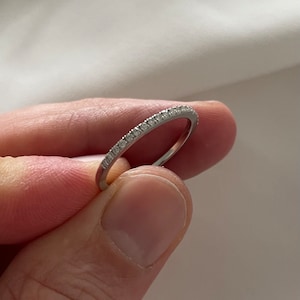 May include: A thin silver band with a row of small diamonds set around the entire ring.