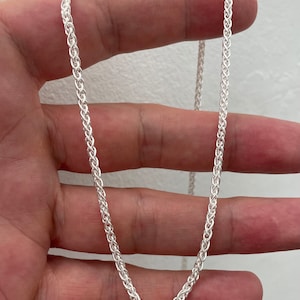 Pu&ograve; includere: Una collana a catena d'argento con un design intrecciato delicato. La catena &egrave; lunga circa 50 cm.
