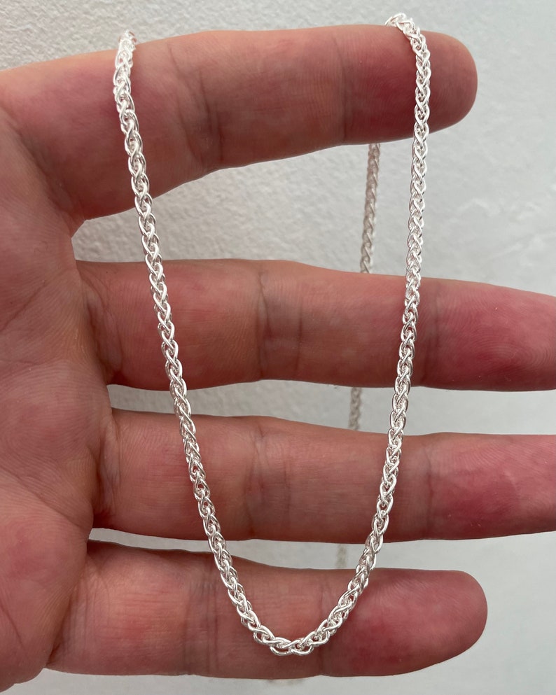 Pu&ograve; includere: Una collana a catena d'argento con un design intrecciato delicato. La catena &egrave; lunga circa 50 cm.