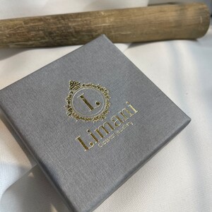 May include: A gray jewelry box with a gold logo that says "Limani Classical Jewelry".