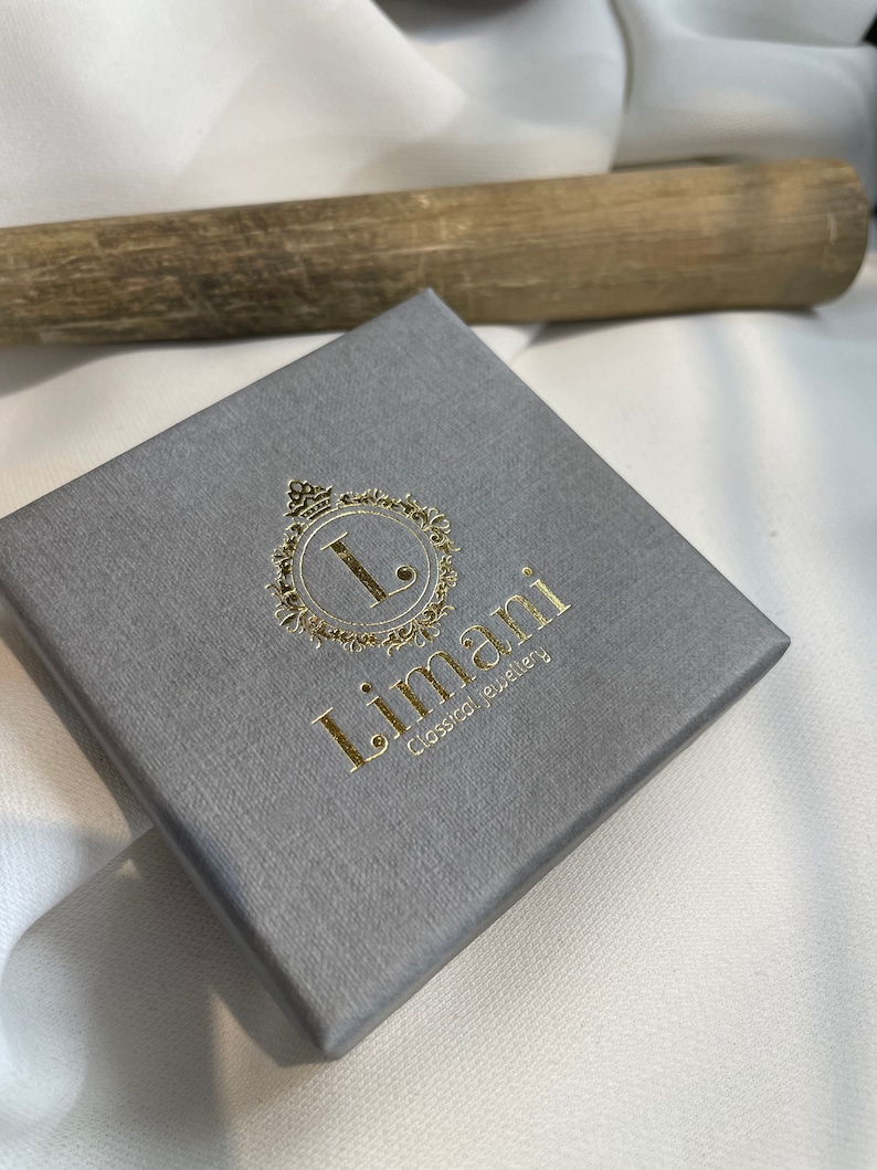 May include: A gray jewelry box with a gold logo that says "Limani Classical Jewelry".