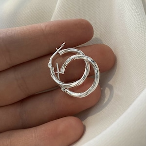 May include: A pair of silver hoop earrings with a twisted design.