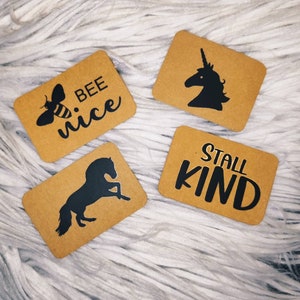 Puede incluir: Cuatro tarjetas de papel marrón con texto negro e ilustraciones. Las tarjetas dicen "Bee Nice", "Stall Kind", y presentan un unicornio y un caballo.