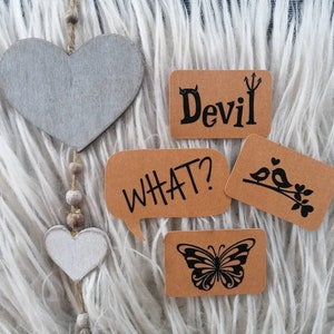 Könnte beinhalten: Vier braune Papierkarten mit schwarzem Text und Bildern. Die Karten sagen "Teufel", "Was?", "Vogel" und "Schmetterling".