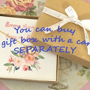 K&ouml;nnte beinhalten: Eine braune Geschenkbox mit einem wei&szlig;en Band und Schleife. Die Box ist mit einem wei&szlig;en Band mit Herzdesign gebunden. Die Box steht auf einer wei&szlig;en Karte mit Blumenmuster und dem Text "Sie k&ouml;nnen eine Geschenkbox mit einer Karte SEPARAT kaufen".