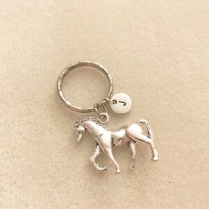 May include: Silver horse keychain with a silver key ring and a silver charm with the letter J.