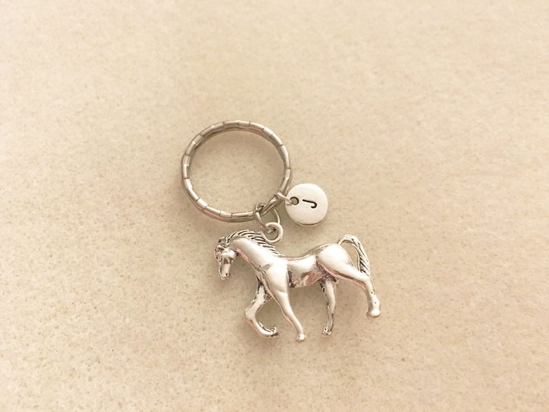 May include: Silver horse keychain with a silver key ring and a silver charm with the letter J.