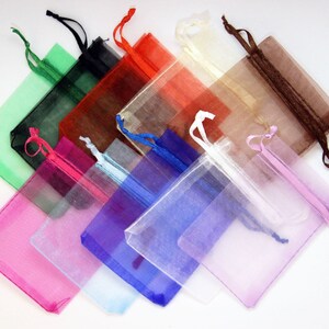 May include: Assortment of colorful organza bags with drawstrings. The bags are made of sheer fabric and come in a variety of colors, including green, black, red, white, brown, pink, blue, and light blue.