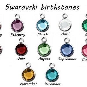May include: A chart showing Swarovski birthstones for each month of the year. The stones are displayed in silver settings. January: red, February: purple, March: blue, April: white, May: green, June: pink, July: red, August: green, September: blue, October: pink, November: gold, December: teal.