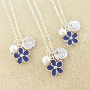Pu&ograve; includere: Tre collane d'argento con ciondoli a forma di fiore blu, perle e dischi d'argento personalizzati. Ogni disco ha una lettera incisa.
