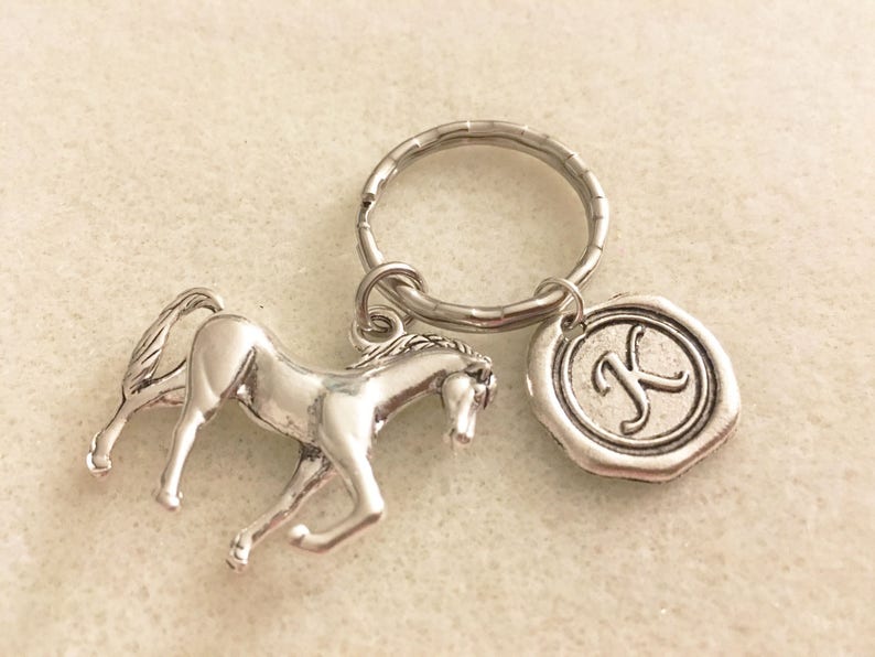 May include: Silver horse keychain with a silver key ring and a silver charm with the letter K.