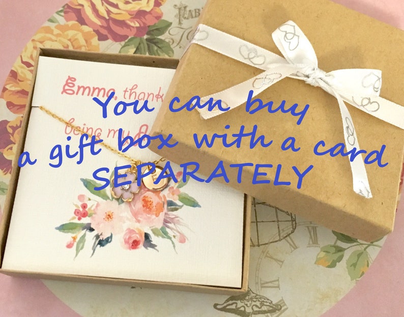 Pu&ograve; includere: Un biglietto bianco con una collana d'oro e un disegno floreale. Il biglietto dice "Puoi acquistare una scatola regalo con un biglietto separatamente".