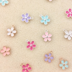 Pu&ograve; includere: Assortimento di ciondoli a forma di fiore smaltati colorati con accenti dorati e argentati. I ciondoli sono perfetti per aggiungere un tocco di fantasia a gioielli, portachiavi o altri lavoretti.