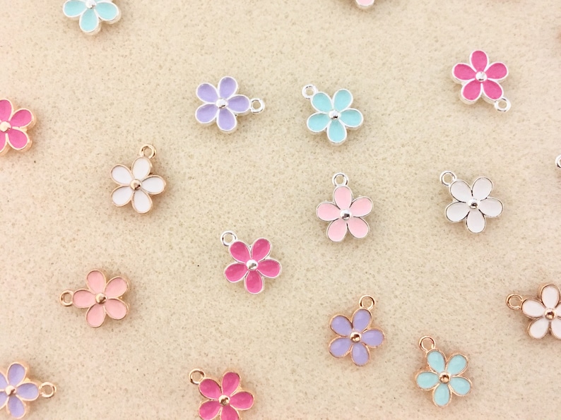Pu&ograve; includere: Assortimento di ciondoli a forma di fiore smaltati colorati con accenti dorati e argentati. I ciondoli sono perfetti per aggiungere un tocco di fantasia a gioielli, portachiavi o altri lavoretti.