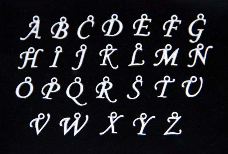 May include: A set of 26 silver-colored metal alphabet charms, each featuring a cursive letter from A to Z. The charms are arranged in three rows on a black background.