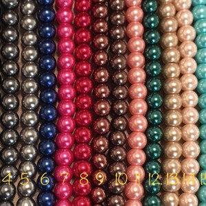 K&ouml;nnte beinhalten: Achtzehn F&auml;den Perlen in verschiedenen Farben, darunter Wei&szlig;, Schwarz, Grau, Blau, Rosa, Rot, Braun, Beige, Teal, T&uuml;rkis, Lavendel und Lila. Die Perlen sind von 1 bis 18 nummeriert.