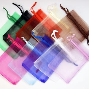 May include: Assortment of colorful organza bags with drawstrings. The bags are made of sheer fabric and come in a variety of colors, including green, black, red, white, brown, pink, blue, and light blue.