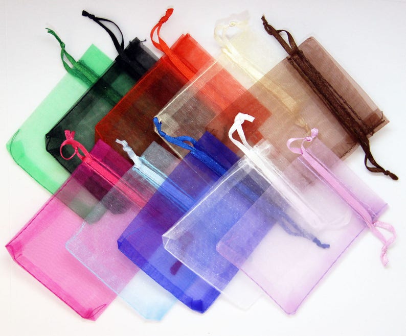 May include: Assortment of colorful organza bags with drawstrings. The bags are made of sheer fabric and come in a variety of colors, including green, black, red, white, brown, pink, blue, and light blue.