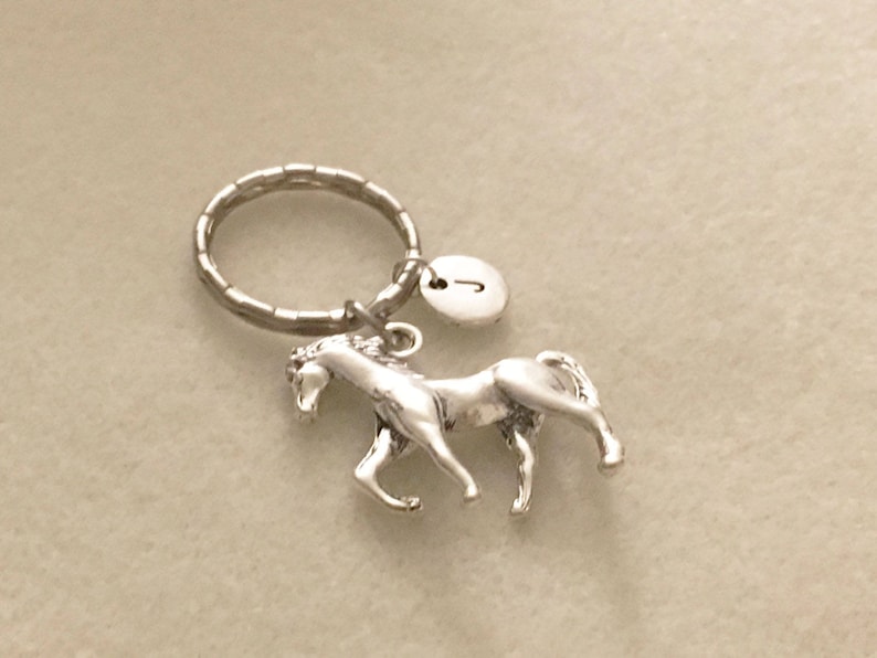 May include: Silver horse keychain with a silver key ring and a silver charm with the letter J.