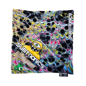 Peut inclure: Un bandana carré aux couleurs vives, avec un motif tourbillonnant jaune, rose, bleu et noir. Le mot "SUBTRONICS" est imprimé en blanc, ainsi qu'un personnage de dessin animé jaune avec un œil. Le texte "CYCLOPS DESERT" est également visible.