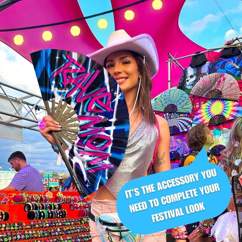 May include: A woman wearing a white cowboy hat holds a blue and pink hand fan with the word "Rave" written in graffiti style. The fan is a festival accessory.