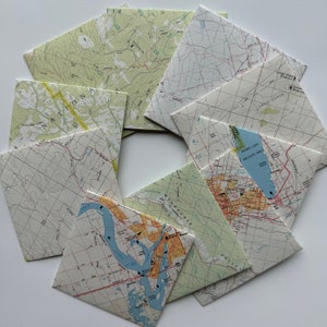May include: A collection of vintage maps, each with a different design and color scheme. The maps are folded and arranged in a circular pattern, with the edges overlapping. The maps are printed on paper and have a worn, aged look.