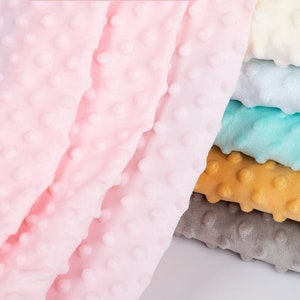 May include: A stack of six different coloured fabrics with a textured, dotted pattern. The fabrics are arranged in a graduated colour scheme from light pink to light yellow.