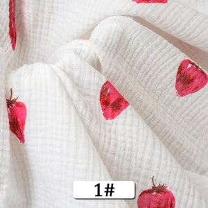 May include: White fabric with a repeating pattern of red strawberries. The fabric is textured and has a crinkled look. The text "1#" is printed on the fabric.