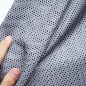 May include: Close-up of a gray fabric with a textured surface. The fabric has a pattern of small, raised dots.
