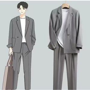 May include: A gray suit with a double-breasted blazer and matching pants. The suit is shown on a mannequin and a person wearing the suit.