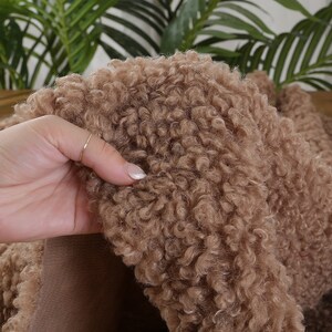 May include: Close-up of a brown faux fur fabric with a soft, fluffy texture.