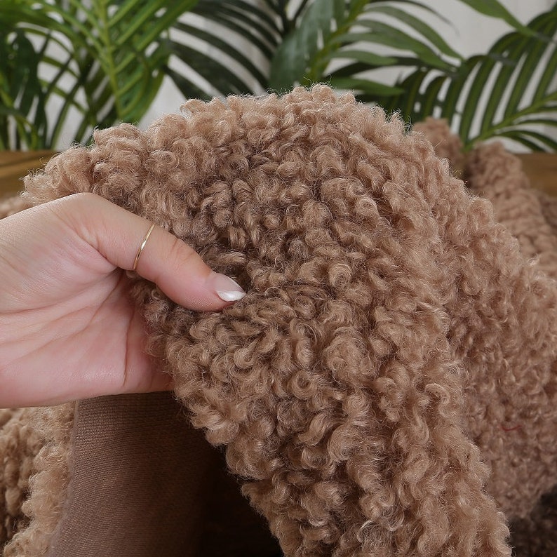 May include: Close-up of a brown faux fur fabric with a soft, fluffy texture.