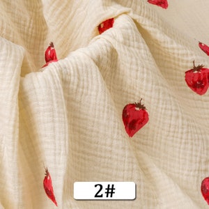 May include: Cream-colored fabric with a subtle waffle texture and a repeating pattern of red strawberries. The fabric has a 2# label.