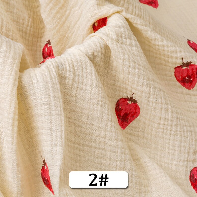 May include: Cream-colored fabric with a subtle waffle texture and a repeating pattern of red strawberries. The fabric has a 2# label.