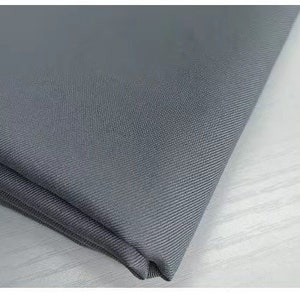 May include: Close-up of a gray fabric with a subtle texture. The fabric is folded and appears to be soft and smooth.
