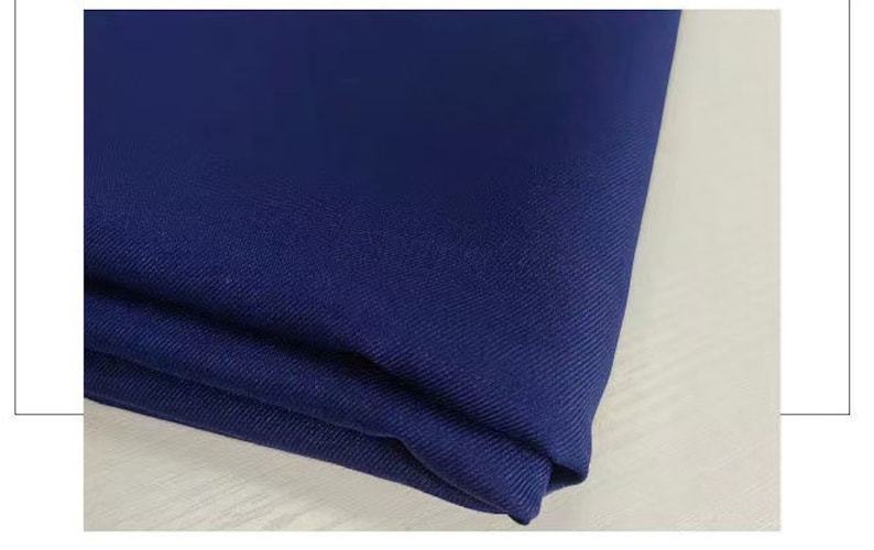 May include: A close-up of a dark blue fabric with a subtle texture. The fabric is folded and appears to be soft and smooth.